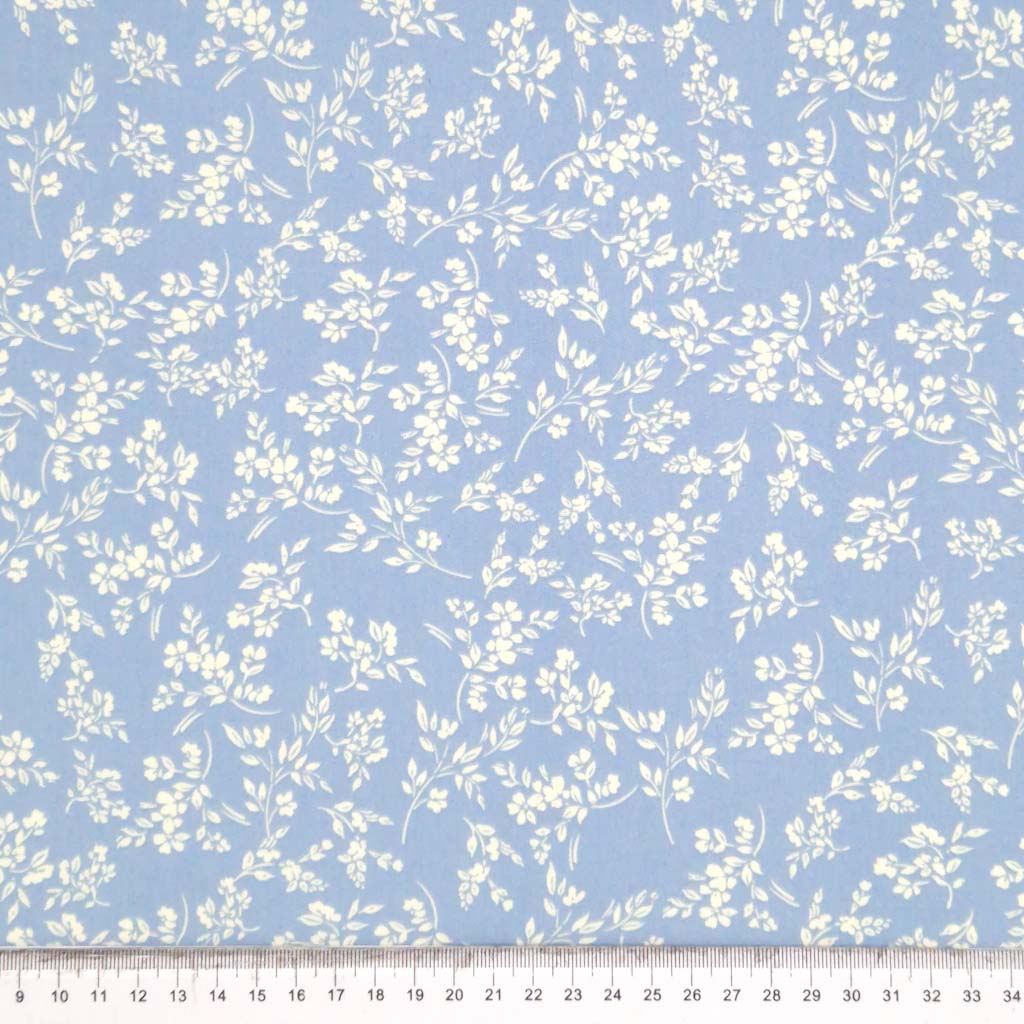 A cream vine floral printed on a sky blue cotton poplin fabric by Rose & Hubble with a cm ruler