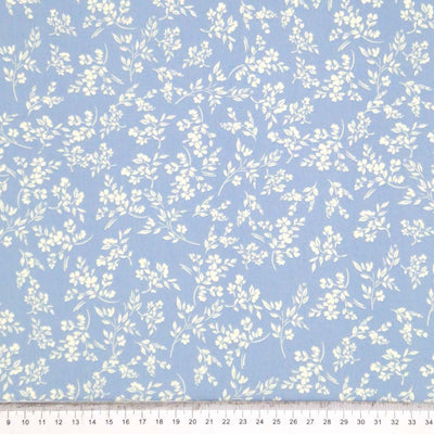 A cream vine floral printed on a sky blue cotton poplin fabric by Rose & Hubble with a cm ruler