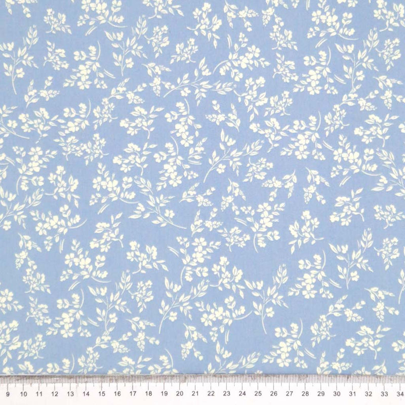 A cream vine floral printed on a sky blue cotton poplin fabric by Rose & Hubble with a cm ruler