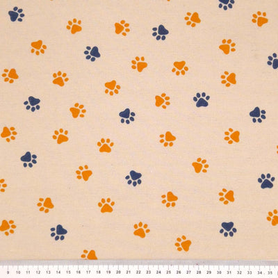 Small paw prints in yellow and black digitally printed on a beige cotton rich, half panama, linen look craft canvas fabric. With a cm ruler