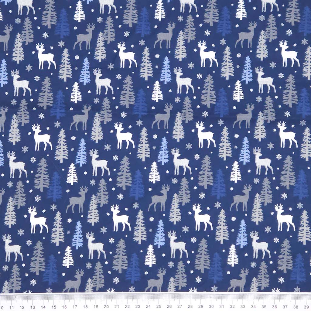 Festive fabric pattern with deer, trees, and snowflakes on a blue christmas cotton fabric.