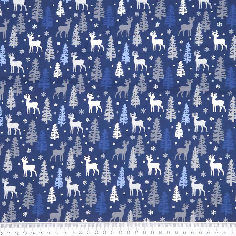 Festive fabric pattern with deer, trees, and snowflakes on a blue christmas cotton fabric.