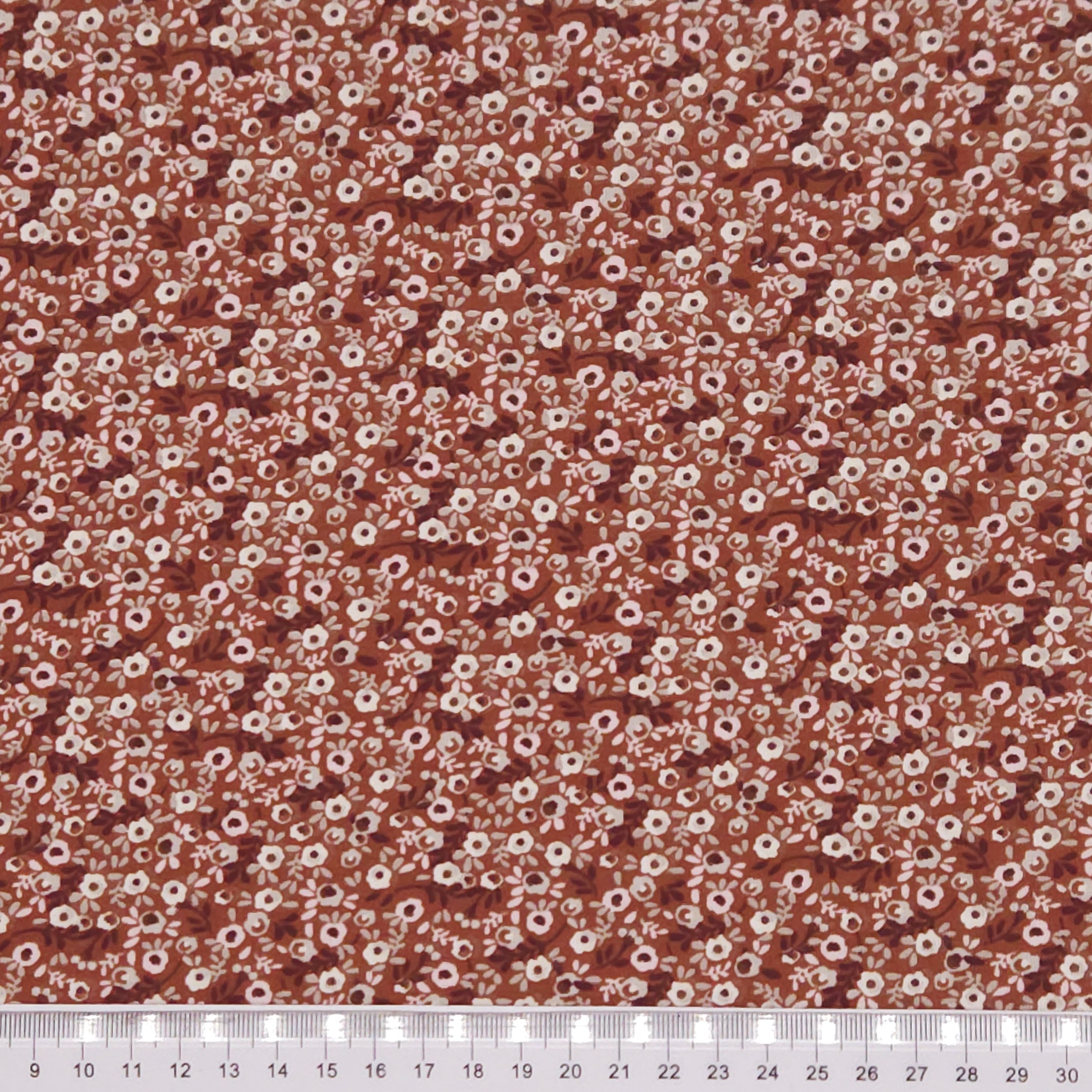 Ditsy flowers printed on a brown cotton jersey fabric with a cm ruler