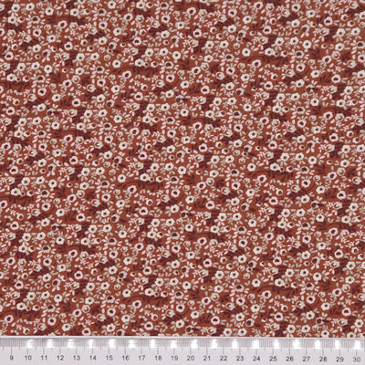 Ditsy flowers printed on a brown cotton jersey fabric with a cm ruler