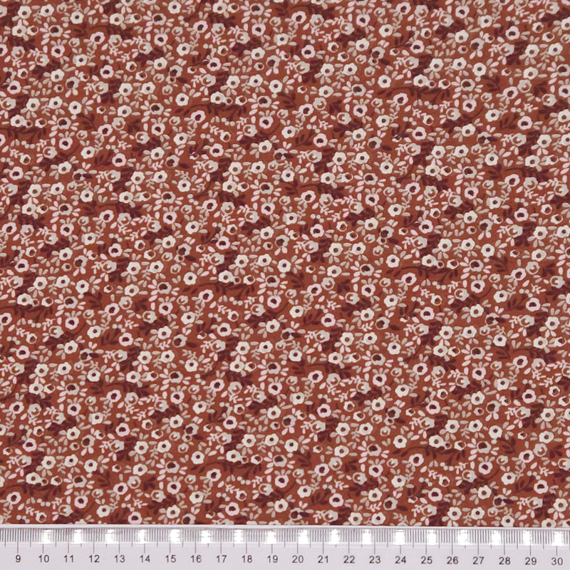 Ditsy flowers printed on a brown cotton jersey fabric with a cm ruler