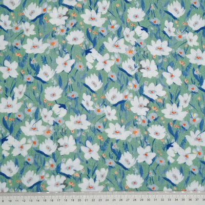 Mystical daisies printed on a sage green double gauze fabric with a cm ruler