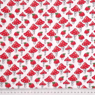 Jolly mushrooms with red caps printed on a white double gauze fabric with a cm ruler