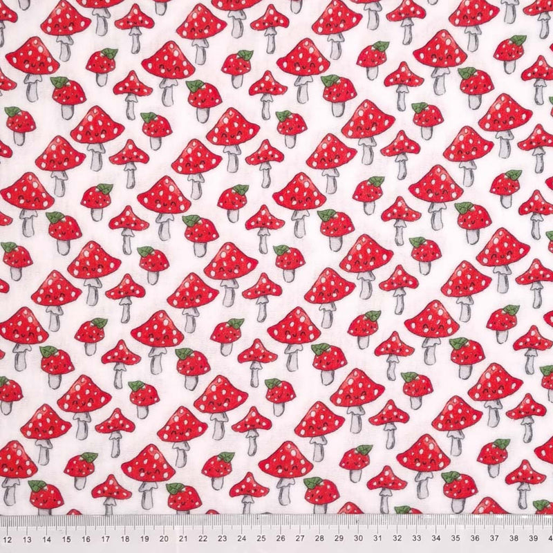 Jolly mushrooms with red caps printed on a white double gauze fabric with a cm ruler