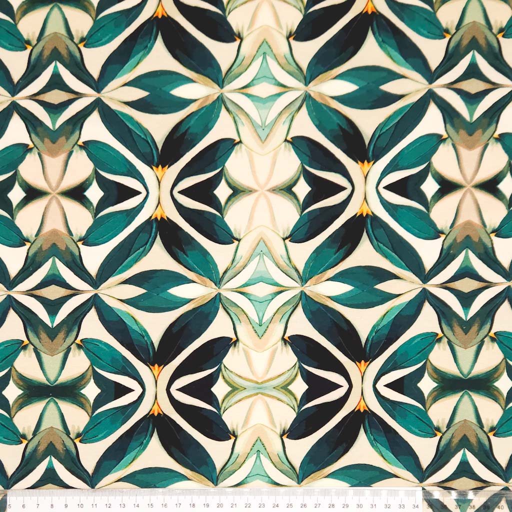 An emerald green mandala pattern printed on a cotton jersey fabric with a cm ruler