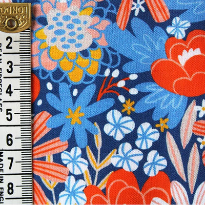 Orange flowers printed with blue foliage on a blue cotton fabric by Little Johnny with a ruler