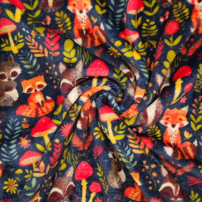 Pattern of foxes, raccoons, and mushrooms on a dark blue cuddle fleece fabric with folds