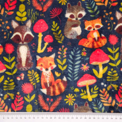 Pattern of foxes, raccoons, and mushrooms on a dark blue cuddle fleece fabric with a cm ruler