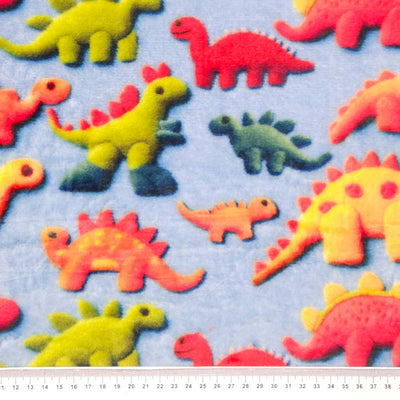 Pattern of colourful dinosaur toys on a blue cuddle fleece with a cm ruler