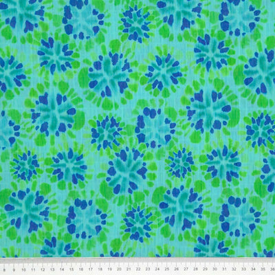 Tie dye flower shapes printed on a green crinkle effect fabric with a cm ruler