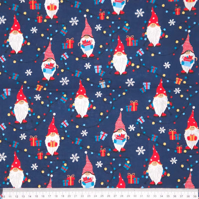 Pattern of Christmas gnomes, presents, and snowflakes on a blue cotton fabric with a ruler