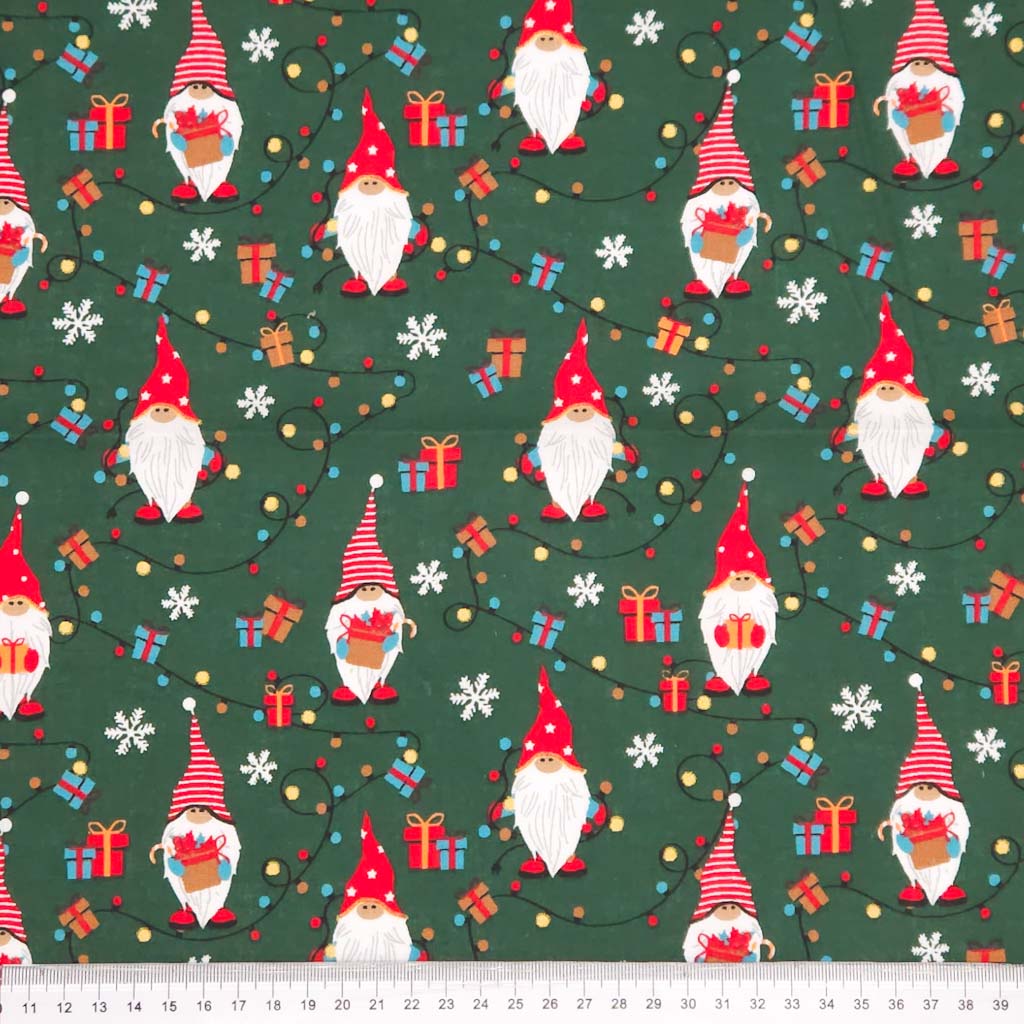 Pattern of Christmas gnomes, presents, and snowflakes on a green cotton fabric with a ruler