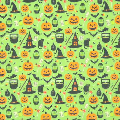 Halloween-themed pattern with pumpkins, cats, and witches' hats on a green polycotton fabric.