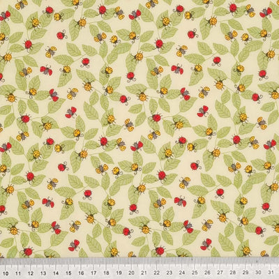 Red and yellow ladybirds printed on an ivory polycotton fabric with a cm ruler 