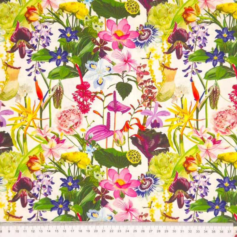 A colourful array of tropical wild flowers and leaves on a contrasting cream linen fabric background with a cm ruler