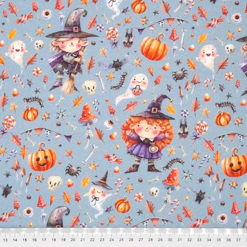 Witches and pumpkins are printed on a grey cotton fabric by Little Johnny with a cm ruler