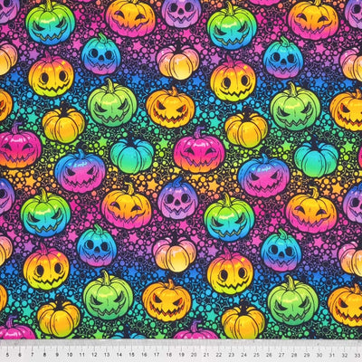 Brightly coloured neon pumpkins are printed on a black cotton fabric by Little Johnny with a cm ruler