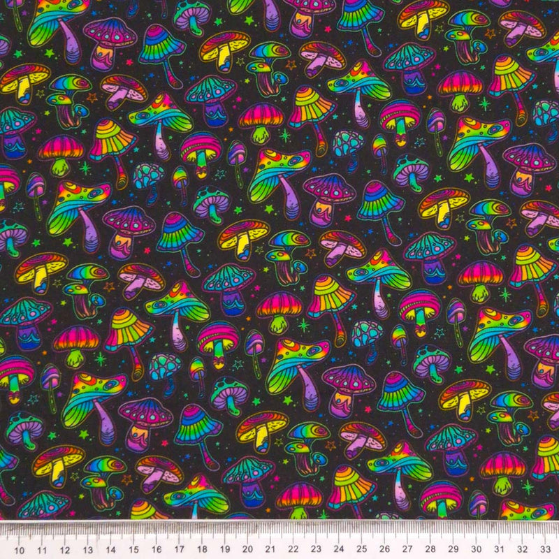 Neon coloured mushrooms printed on a black cotton fabric by Little Johnny with a cm ruler