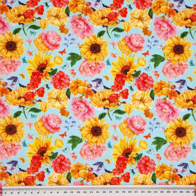 Bright sunflowers and pink roses are printed on a sky blue needlecord fabric with a cm ruler
