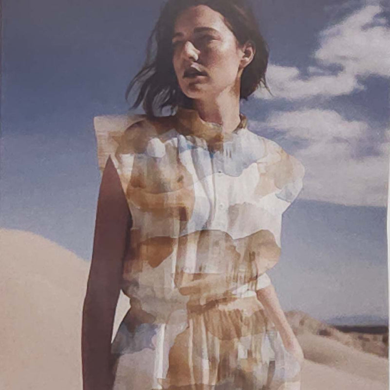 Woman standing in a desert with a blue sky, overlaid with abstract geometric patterns.