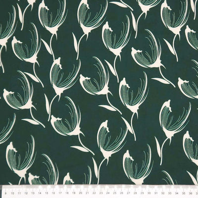 Pattern of white tulips on a dark green viscose twill fabric with a ruler at the bottom.