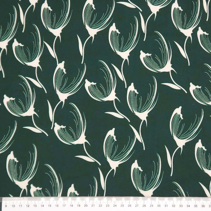 Pattern of white tulips on a dark green viscose twill fabric with a ruler at the bottom.