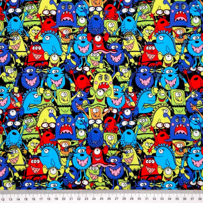 Pattern of colorful cartoon monsters on a black halloween polycotton fabric with a ruler at the bottom.