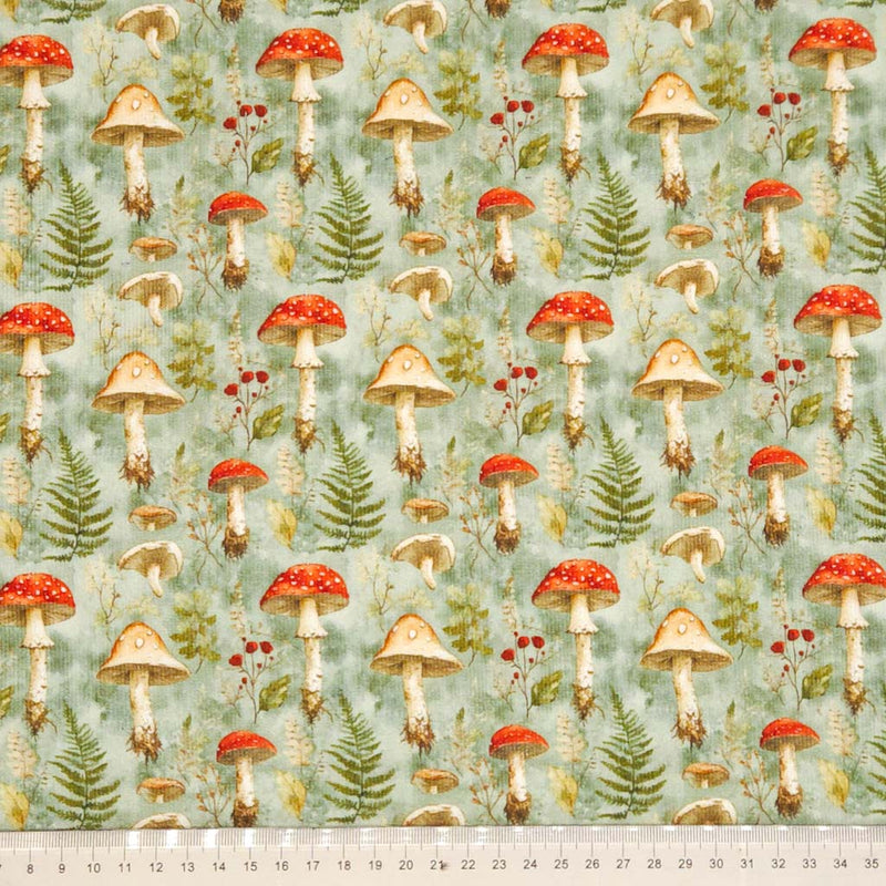 Pattern of mushrooms and foliage on a needlecord fabric with a ruler at the bottom.