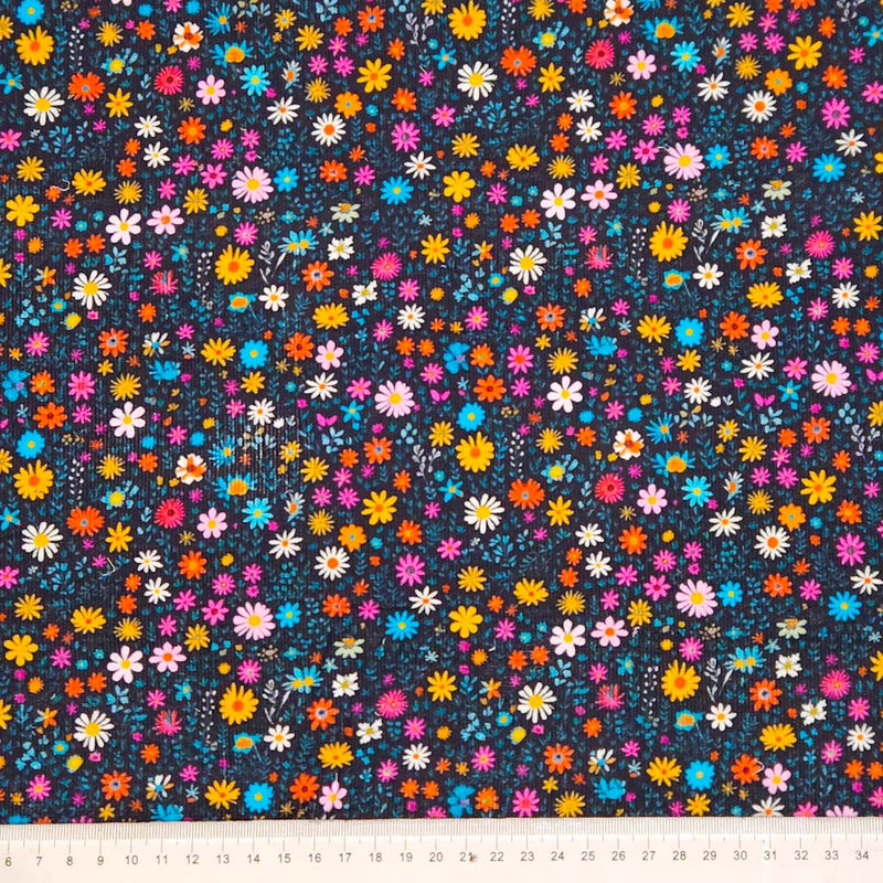 Colorful floral pattern on a dark needlecord fabric with a cm ruler