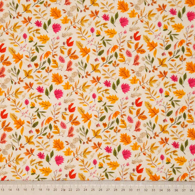 Fabric with autumn leaf pattern on a beige background, ruler at the bottom for scale.