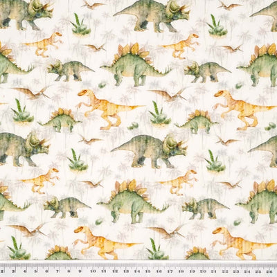 Dinosaurs printed on a white needlecord cotton fabric with a cm ruler