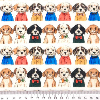 Pattern of small dogs in colourful outfits on a white polycotton fabric with a ruler at the bottom.