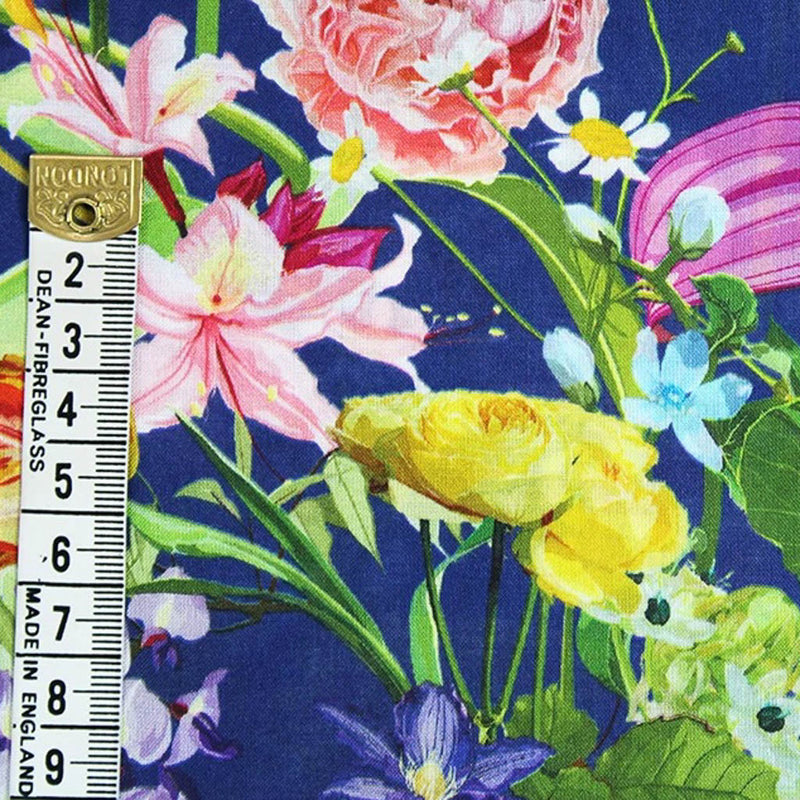 Vibrant summer flowers printed on a royal blue viscose fabric for dressmaking with a cm ruler