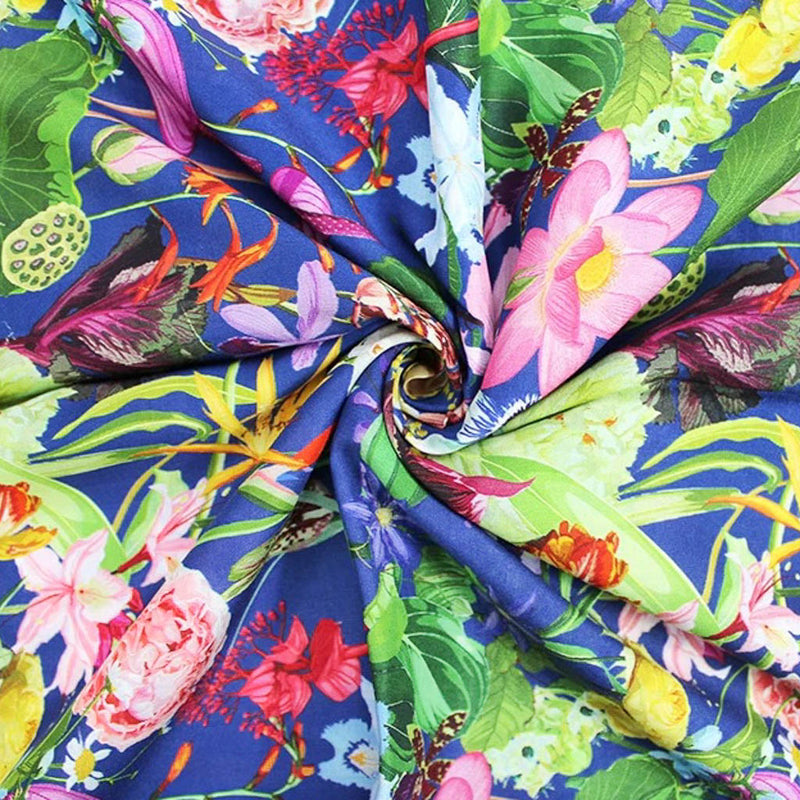 Vibrant summer flowers printed on a royal blue viscose fabric for dressmaking in a swirl