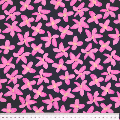 Pattern of pink flowers on a dark pima cotton lawn fabric with a ruler at the bottom.