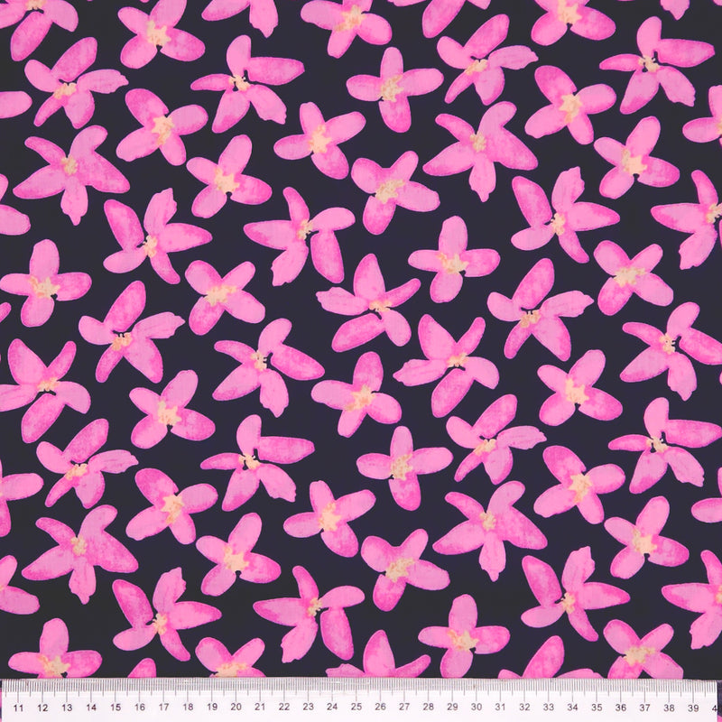 Pattern of pink flowers on a dark pima cotton lawn fabric with a ruler at the bottom.