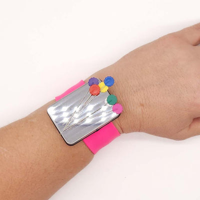 Wrist wearing a colourful pin holder with pins on a white background