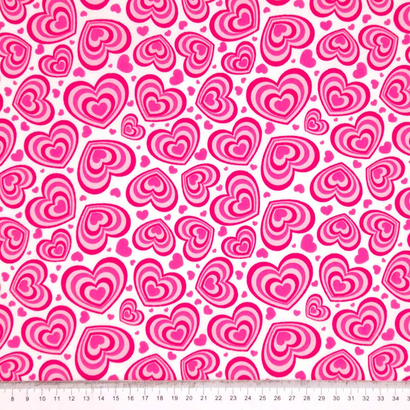 Pink concentric hearts printed on a white polycotton fabric with a cm ruler