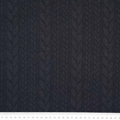 A plain black cable knit fabric with a cm ruler