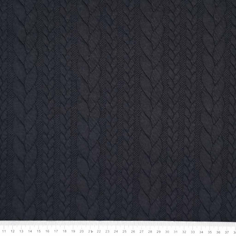 A plain black cable knit fabric with a cm ruler