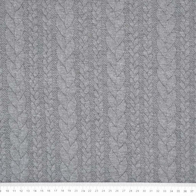 A plain cable knit dressmaking fabric in grey with a cm ruler