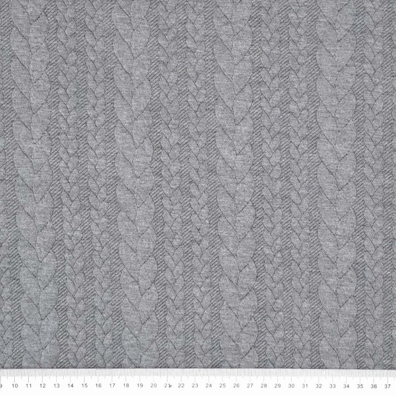 A plain cable knit dressmaking fabric in grey with a cm ruler