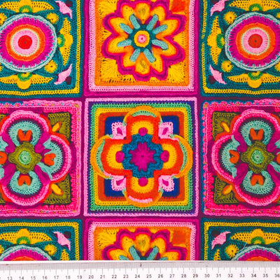 Colourful crocheted squares with floral patterns on a cotton fabric with a cm ruler