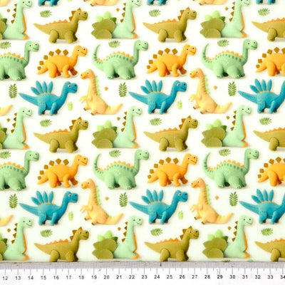 Pattern of colourful cartoon dinosaurs on a white polycotton fabric with a ruler at the bottom.
