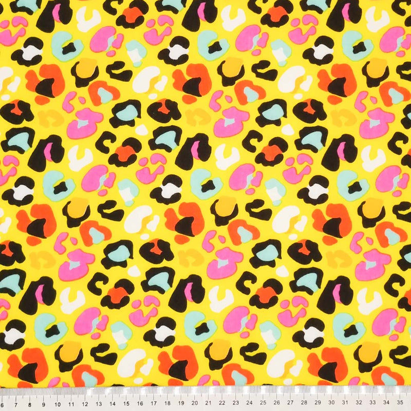 A fun leopard print with colourful leopard spots on a yellow polycotton with a cm ruler.