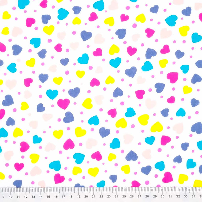 Brightly coloured ditsy hearts printed on a white polycotton fabric with a cm ruler.